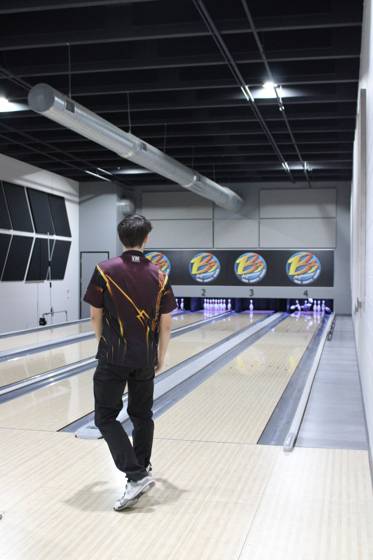 bowling team member watches his ball hit pins